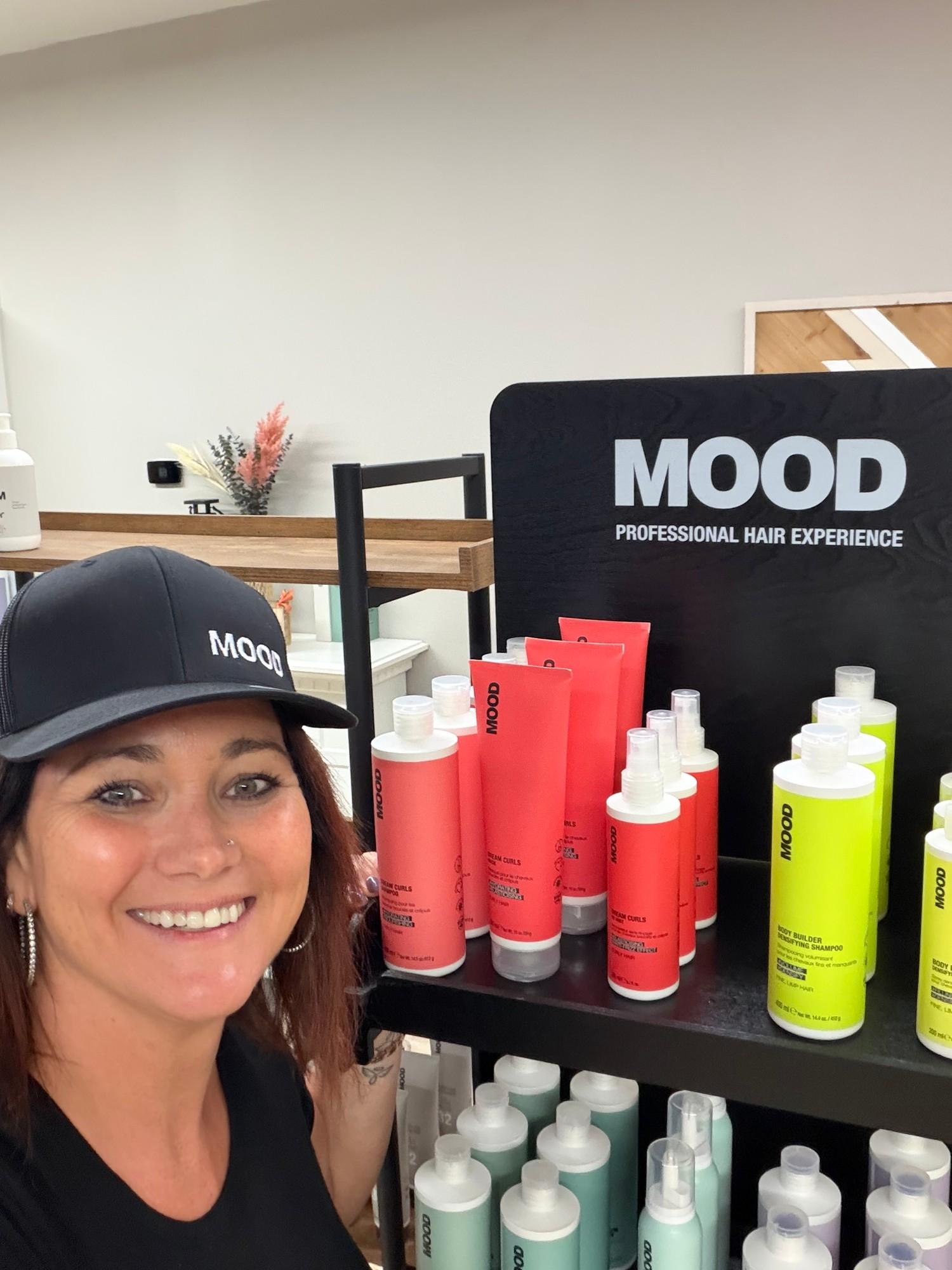 Stephanie, owner of Atria, beside the Mood professional hair display in the salon.